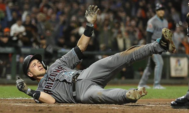 Arizona Diamondbacks' Nick Ahmed tumbles and waits for the call after being thrown out at home plat...