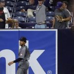 A fan reacts after catching a home run ball hit by the San Diego Padres' Manuel Margot as Arizona Diamondbacks center fielder Jon Jay, below, looks on during the eighth inning of a baseball game Friday, Aug. 17, 2018, in San Diego. (AP Photo/Gregory Bull)