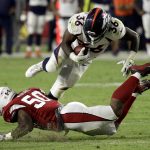 Denver Broncos running back David Williams goes over the top of Arizona Cardinals' Airius Moore during the second half of a preseason NFL football game Thursday, Aug. 30, 2018, in Glendale, Ariz. (AP Photo/Rick Scuteri)