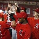 Los Angeles Angels' Kole Calhoun (56) celebrates his run scored against the Arizona Diamondbacks with Justin Upton, middle, and pitching coach Charles Nagy, right, during the third inning of a baseball game, Tuesday, Aug. 21, 2018, in Phoenix. (AP Photo/Ross D. Franklin)
