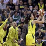 Seattle Storm's Sue Bird, right, shoots a three-point basket as teammates cheer on the bench in the first half of a WNBA basketball playoff semifinal against the Phoenix Mercury, Sunday, Aug. 26, 2018, in Seattle. (AP Photo/Elaine Thompson)