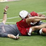 Arizona Cardinals wide receiver Larry Fitzgerald, right, playfully tackles offensive coordinator Mike McCoy, left, after scoring a touchdown during an NFL football practice Saturday, Aug. 4, 2018, in Glendale, Ariz. (AP Photo/Ross D. Franklin)