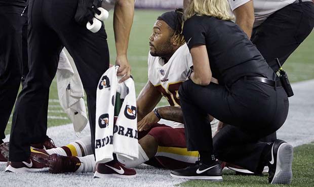Washington Redskins running back Derrius Guice, center, receives attention on the field after an in...