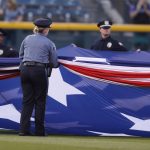 Police officers unfurl an American flag to mark the anniversary of the 9/11 terrorist attacks during a ceremony before a baseball game against the Arizona Diamondbacks, Tuesday, Sept. 11, 2018, in Denver. (AP Photo/David Zalubowski)