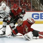 Arizona Coyotes goaltender Antti Raanta, right, makes a diving save on a shot as Los Angeles Kings right wing Jonny Brodzinski (76) and Coyotes defenseman Robbie Russo (34) work for the puck near Raanta during the first period of an NHL preseason hockey game Tuesday, Sept. 18, 2018, in Glendale, Ariz. (AP Photo/Ross D. Franklin)