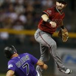 Arizona Diamondbacks second baseman Daniel Descalso, right, jumps over Colorado Rockies' Matt Holliday after forcing him out at second base on the front end of a double play hit into by Ian Desmond to end the fifth inning of a baseball game Wednesday, Sept. 12, 2018, in Denver. (AP Photo/David Zalubowski)