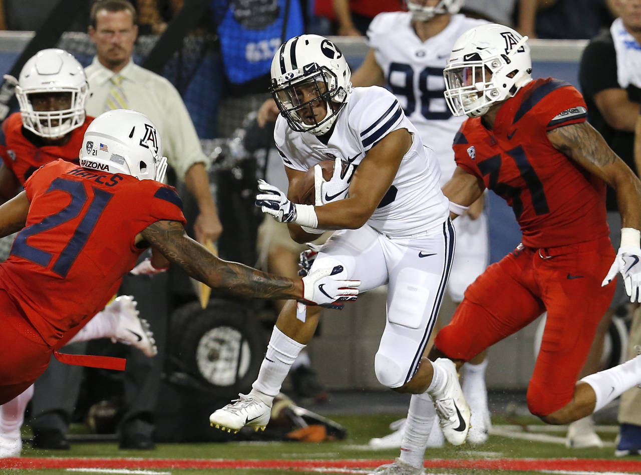 BYU wide receiver Aleva Hifo breaks the tackle by Arizona safety Isaiah Hayes (21) during the first...