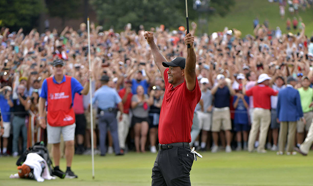 Tiger Woods celebrates after picking up his putt for par on the 18th green to win the final round o...