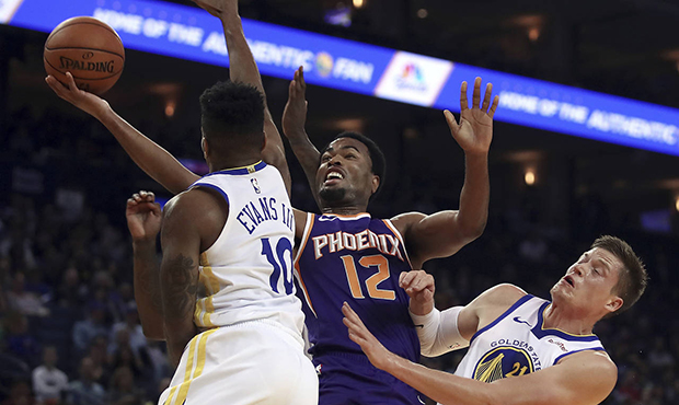 Phoenix Suns' TJ Warren (12) lays up a shot between Golden State Warriors' Jacob Evans, left, and J...