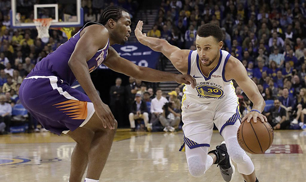Golden State Warriors guard Stephen Curry, right, drives against Phoenix Suns forward TJ Warren dur...