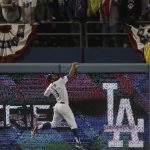 Los Angeles Dodgers' Chris Taylor climbs the left field wall as he watches Red Sox's Mookie Betts' solo home run against Los Angeles Dodgers' Clayton Kershaw during the sixth inning in Game 5 of the World Series baseball game on Sunday, Oct. 28, 2018, in Los Angeles. (AP Photo/Elise Amendola)