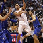 Phoenix Suns guard Devin Booker (1) passes around Dallas Mavericks guard Wesley Matthews (23) during the second half of an NBA basketball game, Wednesday, Oct. 17, 2018, in Phoenix. Booker finished with 35 points in the Suns 121-100 win. (AP Photo/Matt York)