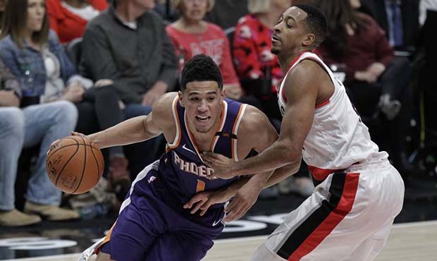 Phoenix Suns guard Devin Booker, left, drives to the basket as Portland Trail Blazers guard CJ McCo...
