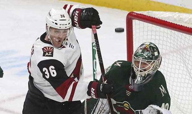 Arizona Coyotes' Christian Fischer, left, tries to position himself while Minnesota Wild's goalie D...