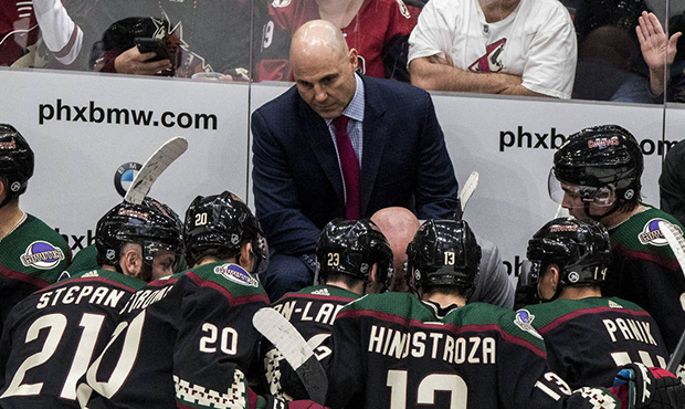 Arizona Coyotes coach Rick Tocchet listens in as a play is called late during the third period of a...