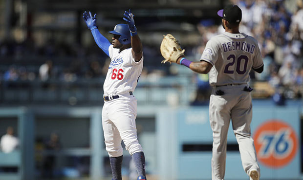 Los Angeles Dodgers' Yasiel Puig, left, reacts to his double as Colorado Rockies' Ian Desmond watch...