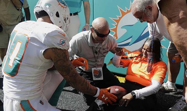 Miami Dolphins wide receiver Kenny Stills (10) gives a football to a security woman he pushes to th...
