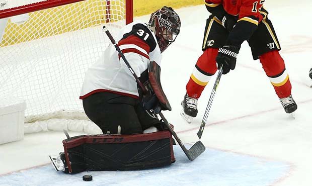 Calgary Flames left wing Johnny Gaudreau (13) has his shot blocked by Arizona Coyotes goaltender Ad...
