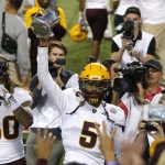 Arizona State quarterback Manny Wilkins (5) celebrates with fans by holding up the Territorial Cup after defeating Arizona in an NCAA college football game, Saturday, Nov. 24, 2018, in Tucson, Ariz. (AP Photo/Rick Scuteri)