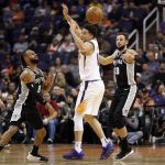 Phoenix Suns guard Devin Booker turns the ball over as San Antonio Spurs guards Patty Mills (8) and Marco Belinelli (18) defend during the first half of an NBA basketball game, Wednesday, Nov. 14, 2018, in Phoenix. (AP Photo/Matt York)