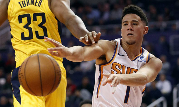 Phoenix Suns guard Devin Booker (1) dishes around Indiana Pacers center Myles Turner (33) during th...