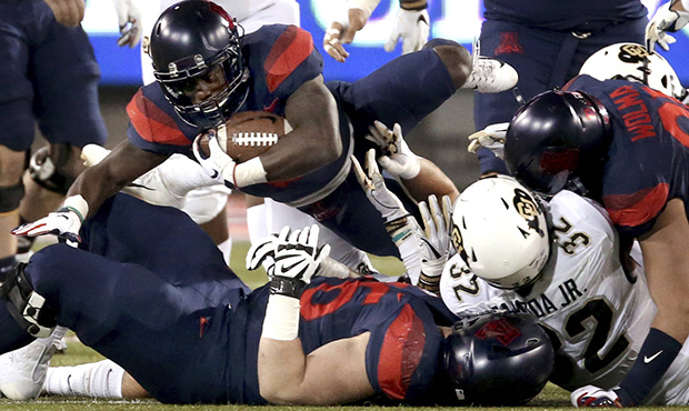 Arizona running back J.J. Taylor (21) throws himself over the pile at the line for an extra yard ag...
