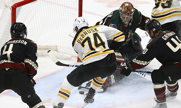 Boston Bruins left wing Jake DeBrusk (74) scores past Arizona Coyotes goaltender Darcy Kuemper, top...
