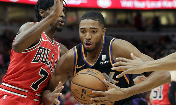 Phoenix Suns forward Mikal Bridges, center, controls the ball between Chicago Bulls guard Justin Ho...