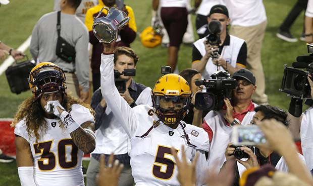 Arizona State quarterback Manny Wilkins (5) celebrates with fans by holding up the Territorial Cup ...