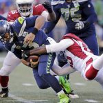 Seattle Seahawks quarterback Russell Wilson, left, is sacked by Arizona Cardinals' Chandler Jones, right, during the first half of an NFL football game, Sunday, Dec. 30, 2018, in Seattle. (AP Photo/John Froschauer)