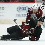 Arizona Coyotes center Nick Schmaltz (8) falls to the ice as he gets hit by Colorado Avalanche center Nathan MacKinnon (29) during the first period of an NHL hockey game Saturday, Dec. 22, 2018, in Glendale, Ariz. (AP Photo/Ross D. Franklin)