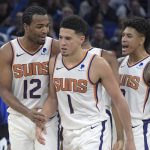 Phoenix Suns guard Devin Booker (1) is congratulated by forward T.J. Warren (12) and forward Kelly Oubre Jr., right, after making a shot during the second half of an NBA basketball game against the Orlando Magic Wednesday, Dec. 26, 2018, in Orlando, Fla. (AP Photo/Phelan M. Ebenhack)