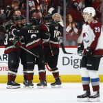 Colorado Avalanche center Nathan MacKinnon (29) skates past as Arizona Coyotes center Derek Stepan, second from left, celebrates his goal with Alex Goligoski (33), Clayton Keller, third from left, and Richard Panik, second from right, during the first period of an NHL hockey game Saturday, Dec. 22, 2018, in Glendale, Ariz. (AP Photo/Ross D. Franklin)