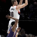 Portland Trail Blazers forward Jake Layman, top, hits a three point basket over Phoenix Suns guard De'Anthony Melton, left, during the first half of an NBA basketball game in Portland, Ore., Thursday, Dec. 6, 2018. (AP Photo/Steve Dykes)