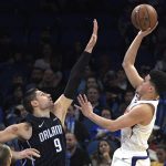 Phoenix Suns guard Devin Booker, right, goes up for a shot in front of Orlando Magic center Nikola Vucevic (9) during overtime of an NBA basketball game Wednesday, Dec. 26, 2018, in Orlando, Fla. (AP Photo/Phelan M. Ebenhack)