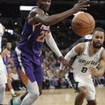 Phoenix Suns center Deandre Ayton (22) and San Antonio Spurs guard Patty Mills (8) chase a loose ball during the first half of an NBA basketball game, Tuesday, Dec. 11, 2018, in San Antonio. (AP Photo/Eric Gay)