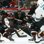 San Jose Sharks left wing Evander Kane (9) sends the puck at Arizona Coyotes goaltender Adin Hill, middle, as Coyotes center Nick Cousins (25) looks on during the second period of an NHL hockey game, Saturday, Dec. 8, 2018, in Phoenix. (AP Photo/Ross D. Franklin)