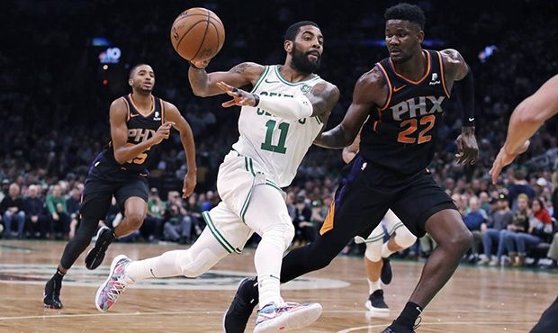 Boston Celtics guard Kyrie Irving (11) passes the ball as he drives against Phoenix Suns center Dea...