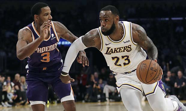 Los Angeles Lakers' LeBron James (23) dribbles next to Phoenix Suns' Trevor Ariza (3) during the se...