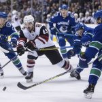 Arizona Coyotes' Conor Garland (83) skates with the puck past Vancouver Canucks' Nikolay Goldobin, back left, of Russia, Troy Stecher, back right, and Derrick Pouliot, front right, during the first period of an NHL hockey game Thursday, Jan. 10, 2019, in Vancouver, British Columbia. (Darryl Dyck /The Canadian Press via AP)