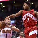 Toronto Raptors guard Kyle Lowry (7) gets a hand to the ball as Phoenix Suns guard Devin Booker (1) drives for the basket during the second half of an NBA basketball game Thursday, Jan. 17, 2019, in Toronto. (Frank Gunn/The Canadian Press via AP)