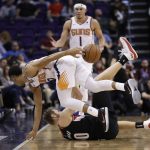 Phoenix Suns guard Elie Okobo, top front, passes around his back after chasing down a loose ball, over Portland Trail Blazers forward Jake Layman during the second half of an NBA basketball game Thursday, Jan. 24, 2019, in Phoenix. (AP Photo/Matt York)