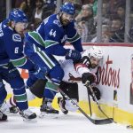 Arizona Coyotes' Brad Richardson (15) reaches for the puck while being checked by Vancouver Canucks' Erik Gudbranson (44) as Brock Boeser (6) takes control of the puck during the first period of an NHL hockey game Thursday, Jan. 10, 2019, in Vancouver, British Columbia. (Darryl Dyck /The Canadian Press via AP)