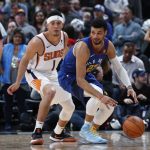 Denver Nuggets guard Jamal Murray, right, reaches out to control the ball as Phoenix Suns guard Devin Booker defends in the first half of an NBA basketball game Friday, Jan. 25, 2019, in Denver. (AP Photo/David Zalubowski)
