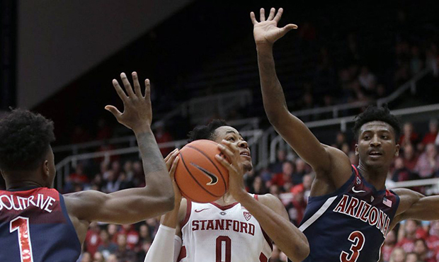 Stanford forward KZ Okpala (0) shoots between Arizona guards Devonaire Doutrive (1) and Dylan Smith...