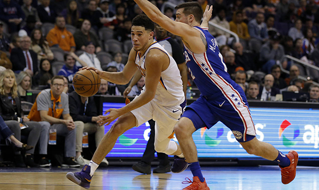 Phoenix Suns guard Devin Booker (1) drives past Philadelphia 76ers guard T.J. McConnell in the firs...