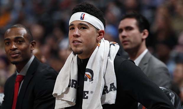 Phoenix Suns guard Devin Booker watches from the bench near the end of the team's NBA basketball ga...