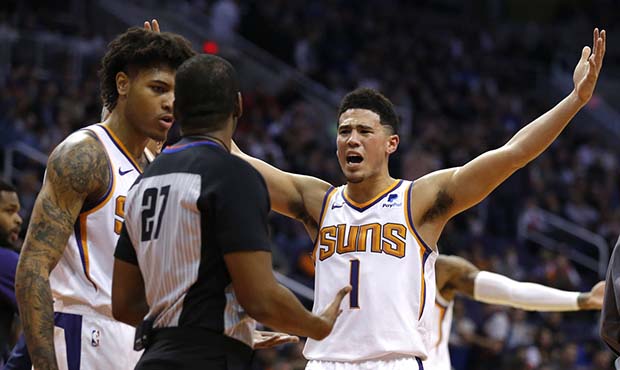 Phoenix Suns guard Devin Booker (1) reacts after a foul call with NBA official Mitchell Ervin (27) ...