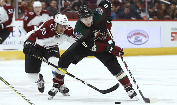 Arizona Coyotes center Nick Schmaltz (8) tries to keep the puck away from Colorado Avalanche left w...