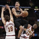 Phoenix Suns' Devin Booker, center, drives to the basket between Cleveland Cavaliers' Matthew Dellavedova, left, and David Nwaba in the second half of an NBA basketball game, Thursday, Feb. 21, 2019, in Cleveland. (AP Photo/Tony Dejak)
